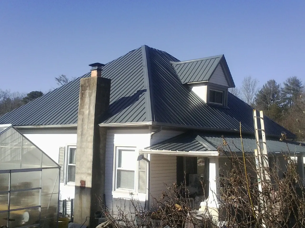 Dark blue standing seam metal roof on a white farmhouse with dormer — Slate & Tile Roof Repair by Roofing Brothers in Cocolamus