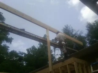 Carpenter setting a ridge beam over a new addition frame — Ice Dam Removal by Roofing Brothers in Cocolamus