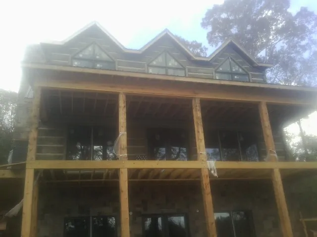 Dormers and porch framing on a large log home under construction — Roof Coating work by our crew in Cocolamus