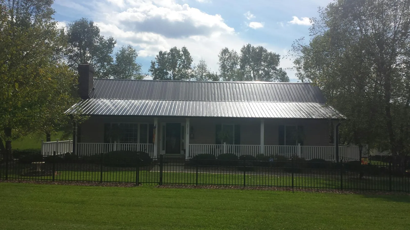 Gray metal roof on a brick ranch with a full width front porch — Gutter Guard Installation work by our crew in Cocolamus
