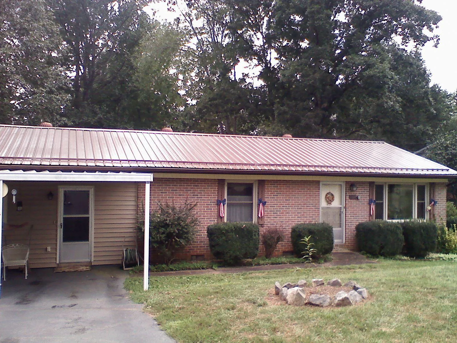 Bronze metal roof and carport on a brick ranch home — Roof Repair work by our crew in Cocolamus