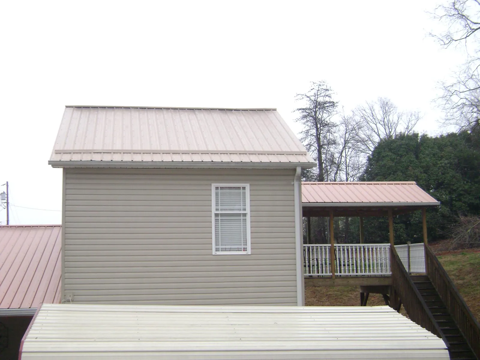 Tan metal roofs on a two story addition and attached porch, from a Roof Replacement job in Cocolamus