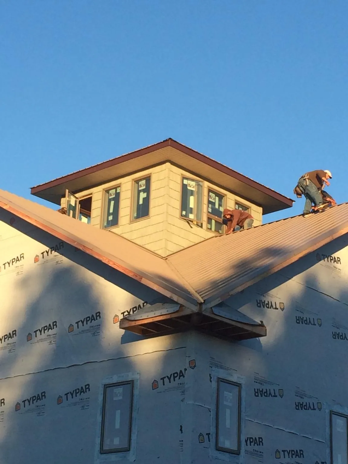 Roofers working around a rooftop cupola on a new metal roof at sunset — Roof Waterproofing in Cocolamus by Roofing Brothers